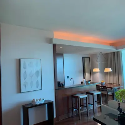 a living room with a kitchen and a bar with stools at One Bal Harbour Ritz Bal Harbour in Miami Beach