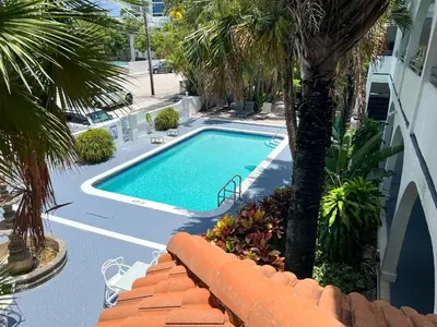 a swimming pool with a palm tree next to a building at Tropi Rock in Fort Lauderdale