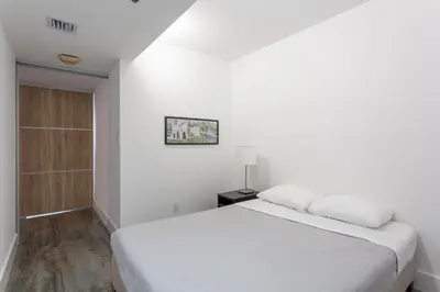 a white bedroom with a bed and a lamp at 4 BDR Sweeping Bayfront Elegance in Miami