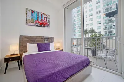 a bedroom with a purple bed and a large window at Miami Brickell 4 Bedrooms High Ceiling loft on the pool in Miami