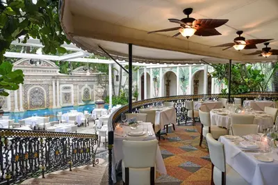 a restaurant with white tables and chairs and a ceiling at The Villa Casa Casuarina in Miami Beach