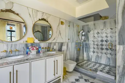 a bathroom with two sinks and a toilet and two mirrors at The Villa Casa Casuarina in Miami Beach