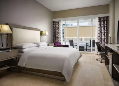 a bedroom with a large white bed and a desk and a room with a balcony at DoubleTree by Hilton Grand Hotel Biscayne Bay in Miami