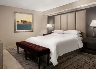 a bedroom with a large white bed and a bench at DoubleTree by Hilton Grand Hotel Biscayne Bay in Miami