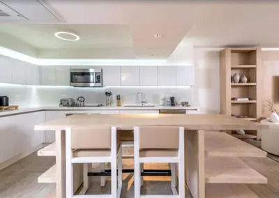 a kitchen with a wooden table and white cabinets at 1 Hotel & Homes Miami Beach Oceanfront Residence Suites By Joe Semary in Miami Beach