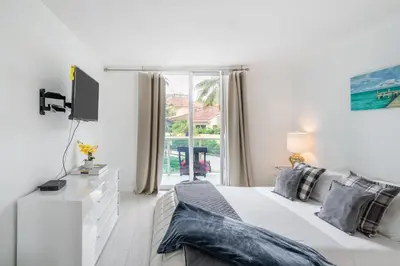 a white bedroom with a bed and a tv at Luxury Miami Condos in Miami Beach