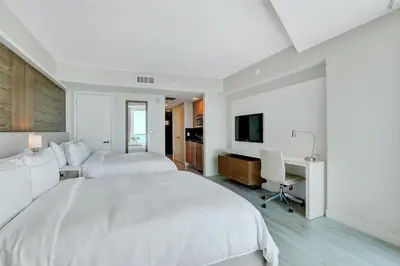 a bedroom with two beds and a desk and a television at Beach House Fort Lauderdale, A Hilton Resort in Fort Lauderdale