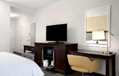 a bedroom with a desk with a television and a chair at Hampton Inn Hallandale Beach-Aventura in Hollywood