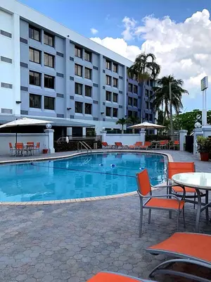 a hotel pool with tables and chairs and a hotel at Holiday Inn Express & Suites Miami - Hialeah by IHG in Hialeah