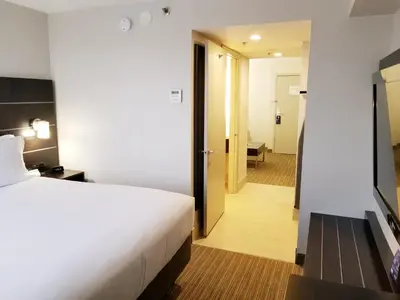 a hotel room with a bed and a hallway at Holiday Inn Express & Suites Miami - Hialeah by IHG in Hialeah