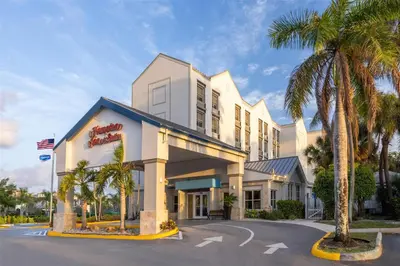 a hotel with palm trees in front of it at Hampton Inn & Suites Fort Lauderdale Airport in Hollywood
