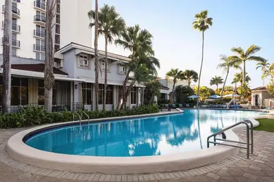 a swimming pool at a resort with palm trees at Embassy Suites by Hilton Fort Lauderdale 17th Street in Fort Lauderdale
