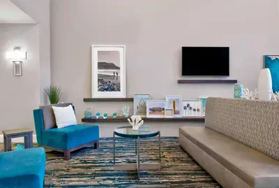 a living room with a couch and a table and a tv at Hampton Inn Ft Lauderdale Airport North Cruise Port in Fort Lauderdale