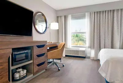a hotel room with a desk with a television and a bed at Hampton Inn Ft Lauderdale Airport North Cruise Port in Fort Lauderdale