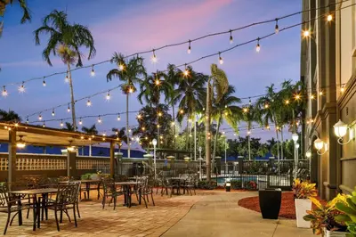 a patio with tables and chairs and lights at La Quinta by Wyndham Miami Airport West in Miami