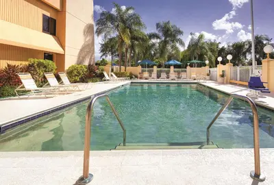 a swimming pool at a hotel with chairs and a building at La Quinta by Wyndham Miami Airport East in Miami