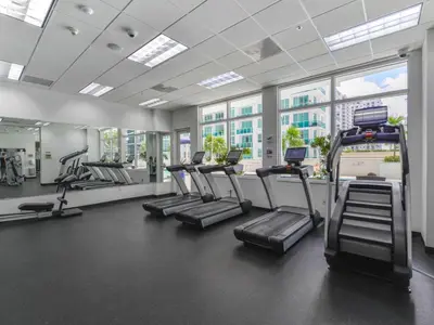 a gym with rows of treadmills and elliptical machines at Beautiful Apartment in the Heart of Brickell in Miami