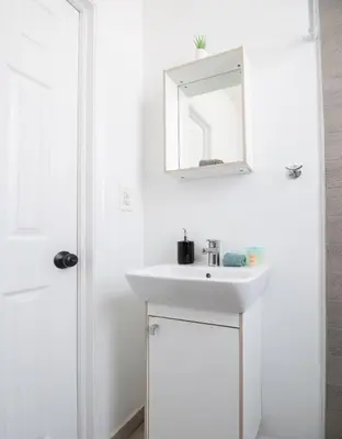 a white bathroom with a sink and a mirror at Apartments in the Heart of Miami - Port of Miami / Miami Airport in Miami