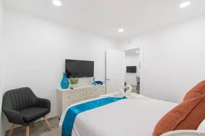 a bedroom with a bed and a chair and a television at Modern apt wqueen bed beach steps in Hollywood