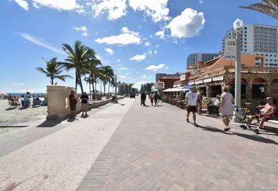 people walking on a sidewalk next to the beach at Modern apt wqueen bed beach steps in Hollywood