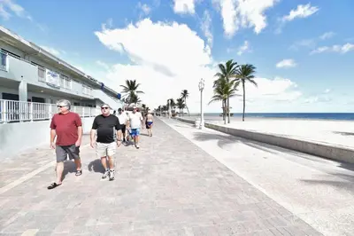 a group of people walking down a sidewalk near the beach at Modern apt wqueen bed beach steps in Hollywood