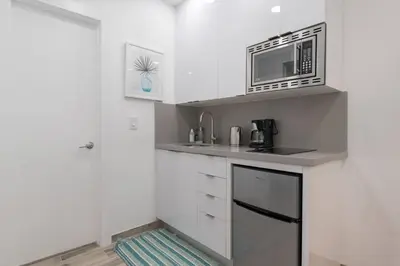 a kitchen with white cabinets and a microwave at Renovated studio w ocean views boardwalk steps in Hollywood