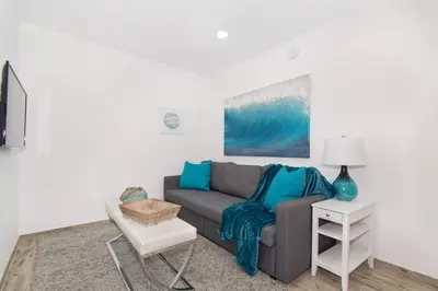 a living room with a gray couch and blue pillows at Renovated studio w ocean views boardwalk steps in Hollywood