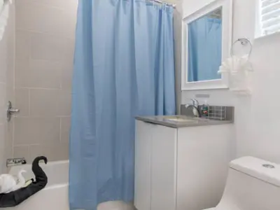 a bathroom with a blue shower curtain and a sink at Modern apartment wking bed steps to beach in Hollywood
