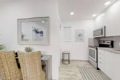 a kitchen with white walls and a table and chairs at Modern apartment wking bed steps to beach in Hollywood