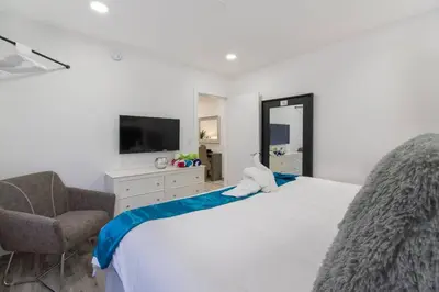 a bedroom with a bed and a chair and a television at Modern apartment wking bed steps to beach in Hollywood