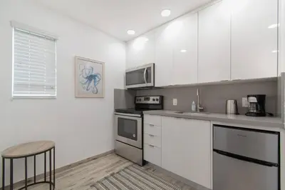 a kitchen with white cabinets and a stove top oven at Modern apartment wking bed steps to beach in Hollywood