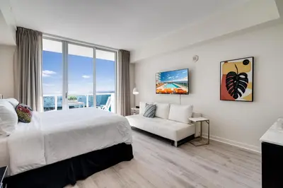a hotel room with a bed and a couch at Ocean View Balcony steps from Restaurants, Peacock Park & Marina in Miami