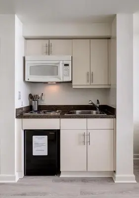 a kitchen with white cabinets and a sink and a microwave at Ocean View Balcony steps from Restaurants, Peacock Park & Marina in Miami