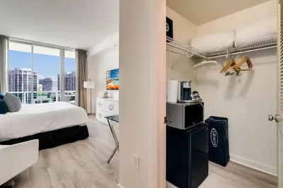 a bedroom with a bed and a desk in a room at City View Balcony steps from Restaurants, Peacock Park & Marina in Miami