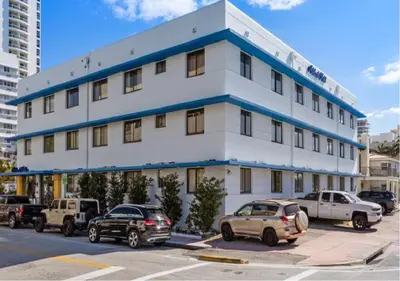 a white building with cars parked in a parking lot at Notebook Miami Beach in Miami Beach
