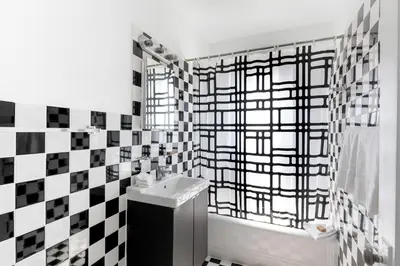 a bathroom with a sink and a black and white checkered wall at Notebook Miami Beach in Miami Beach