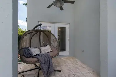 a room with a chair with pillows and a ceiling fan at Spacious 5BR home w heated pool fire pit in Hollywood