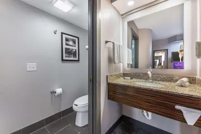 a bathroom with a toilet and a sink and a mirror at Sleep Inn Miami Airport in Miami