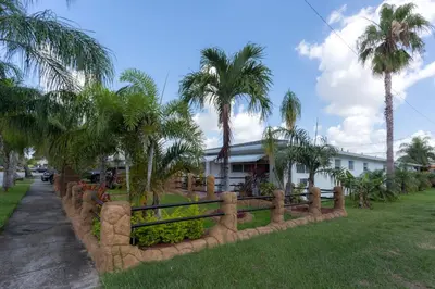 a fence in front of a house with palm trees at Green Seas Motel in Hollywood