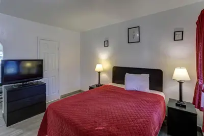 a bedroom with a red bed and a tv at Richard's Motel Extended Stay in Hallandale Beach