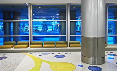a lobby with a waiting area with benches and windows at Miami International Airport Hotel in Miami