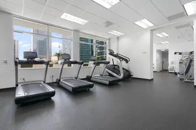 a gym with treadmills and machines in a room with windows at Centric Modern, Stylish Brickell / Miami + FREE Parking in Miami