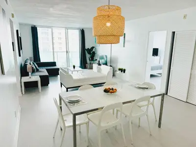 a white living room with a table and chairs at Miami Hallandale Condo, Partial Ocean View Direct Beach and Pool Access Miami Hollywood Beach in Hollywood
