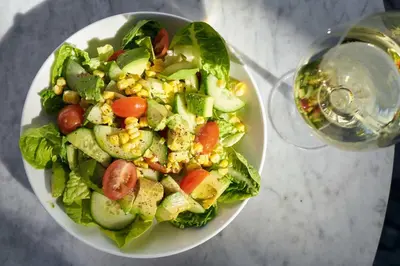 a salad in a white bowl next to a glass of water at Gale South Beach, Curio Collection By Hilton in Miami Beach
