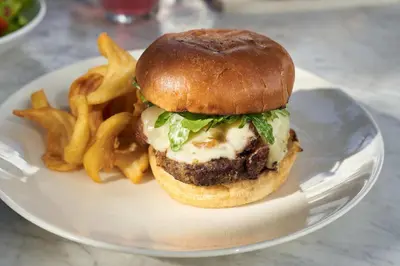 a white plate with a cheeseburger and french fries at Gale South Beach, Curio Collection By Hilton in Miami Beach