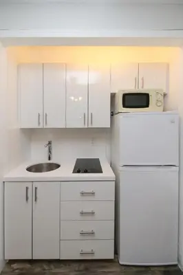 a white kitchen with a sink and a refrigerator at The Dolphin Hollywood in Hollywood