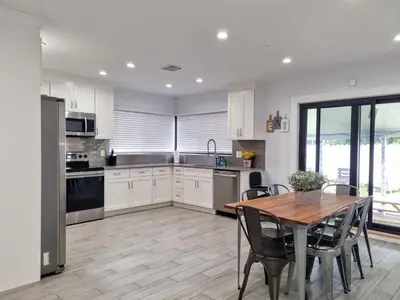 a kitchen with white cabinets and a wooden table with chairs at Downtown Hollywood - 3 miles to Beach - Sleeps 8 in Hollywood