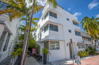 a white building with palm trees in front of it at Posh South Beach in Miami Beach