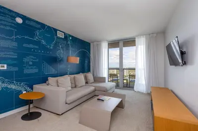 a living room with a couch and a blue wall at Private Ocean Luxury Condos at Beachwalk Resort in Hallandale Beach