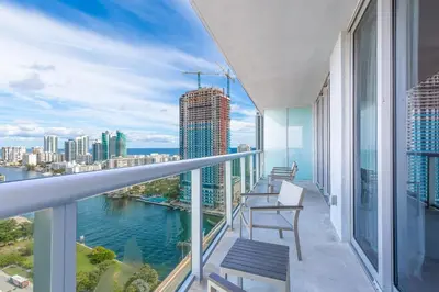 a balcony with chairs and a view of the city at Private Ocean Luxury Condos at Beachwalk Resort in Hallandale Beach